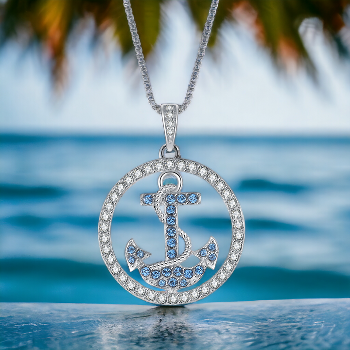 Ankerkette aus 925er Silber vor dem Meer – blauer Anker mit funkelnden Zirkonia, Symbol fuer Liebe, Halt und Vertrauen