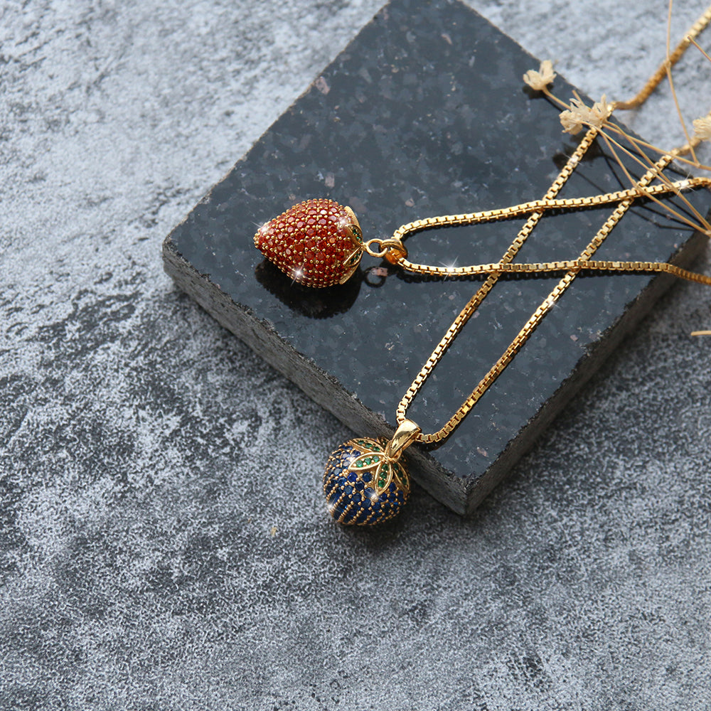 Set aus zwei Erdbeer-Halsketten in Blau und Rot mit goldenen Ketten – fruchtiger Halsschmuck im trendigen Design, ideal als Geschenk