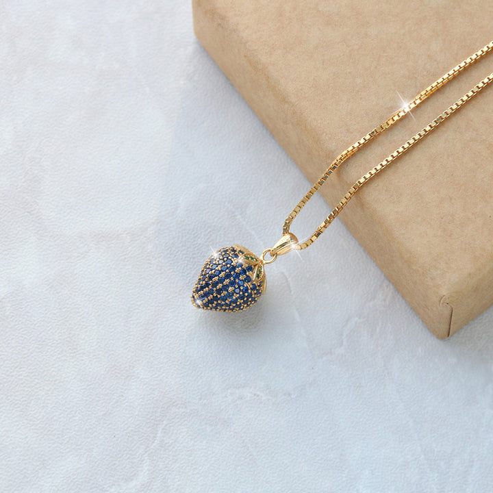 Blaue Erdbeer-Halskette mit goldener Kette auf Geschenkbox – ideal als romantisches Geschenk für Frauen oder Freundin