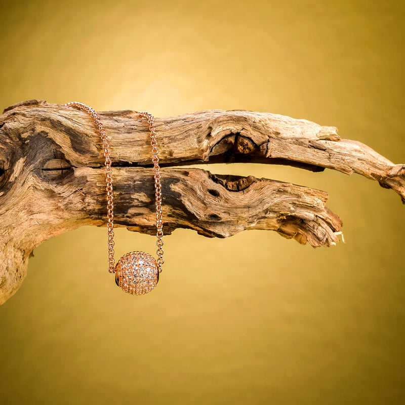 Schmuckstück Halskette Grace Roségold mit Zirkonia inszeniert auf rustikalem Holz – luxuriöses Natur-Setting.