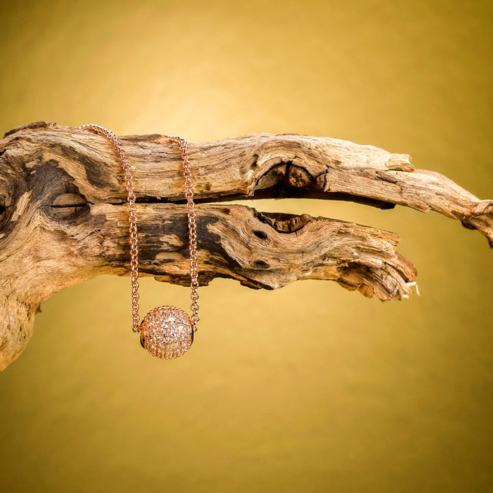 Schmuckstück Halskette Grace Roségold mit Zirkonia inszeniert auf rustikalem Holz – luxuriöses Natur-Setting.