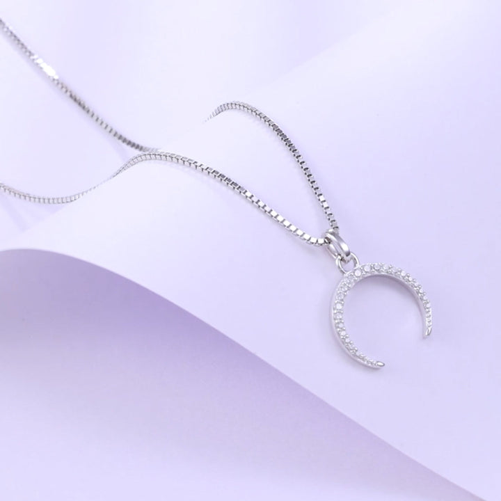 Silberne Halbmondkette mit Zirkonia auf lila Hintergrund – moderner Damenschmuck mit spiritueller Symbolik und feinem Glanz“
