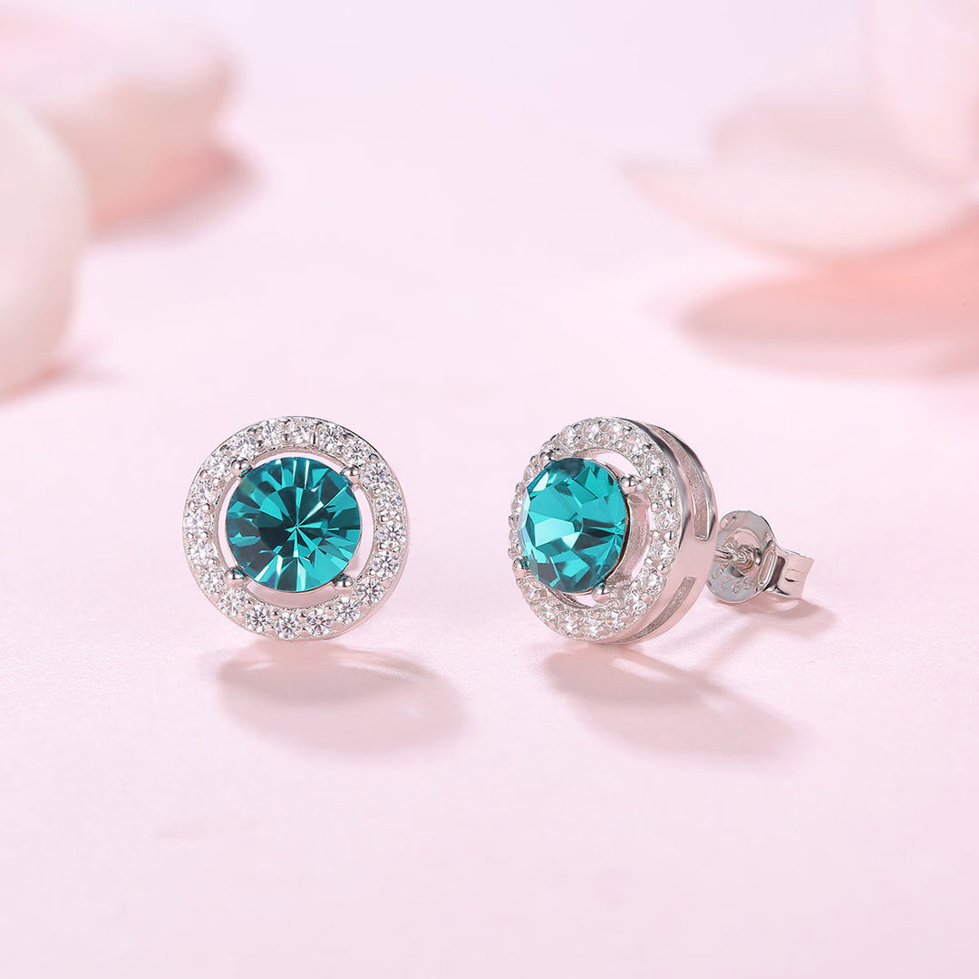 Detailaufnahme der Ohrstecker Blue Silber mit türkisblauem 5A Zirkonia und rhodiniertem 925er Silber auf rosa Hintergrund