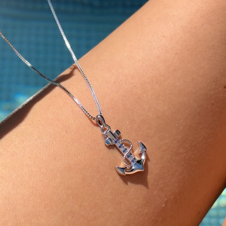 Silberne PAVELS Ankerkette mit Anker-Anhänger am Dekolleté vor blauem Pool