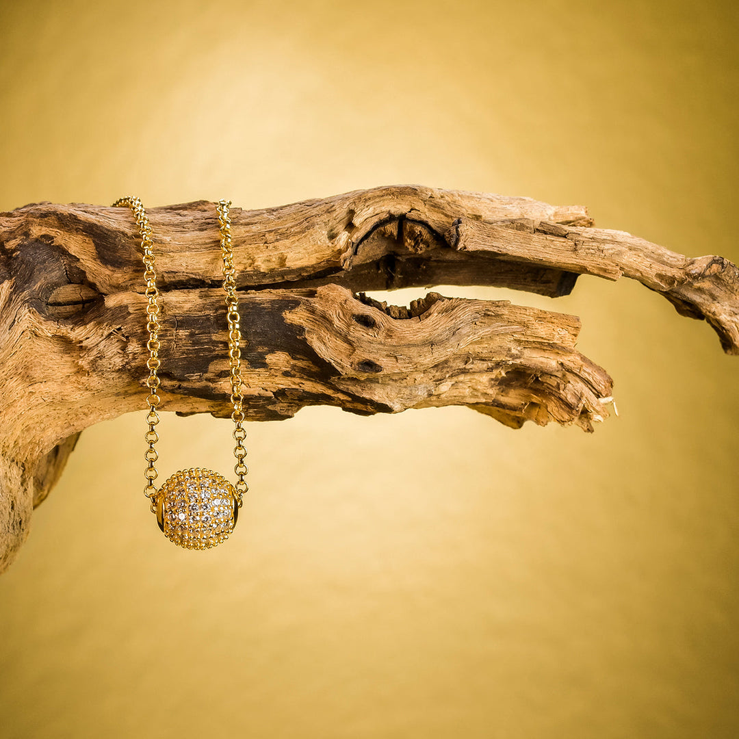 Golden Grace Kette mit Kugelanhänger aus vergoldetem 925 Silber – inszeniert auf Ast – luxuriöser Schmuck mit natürlicher Eleganz